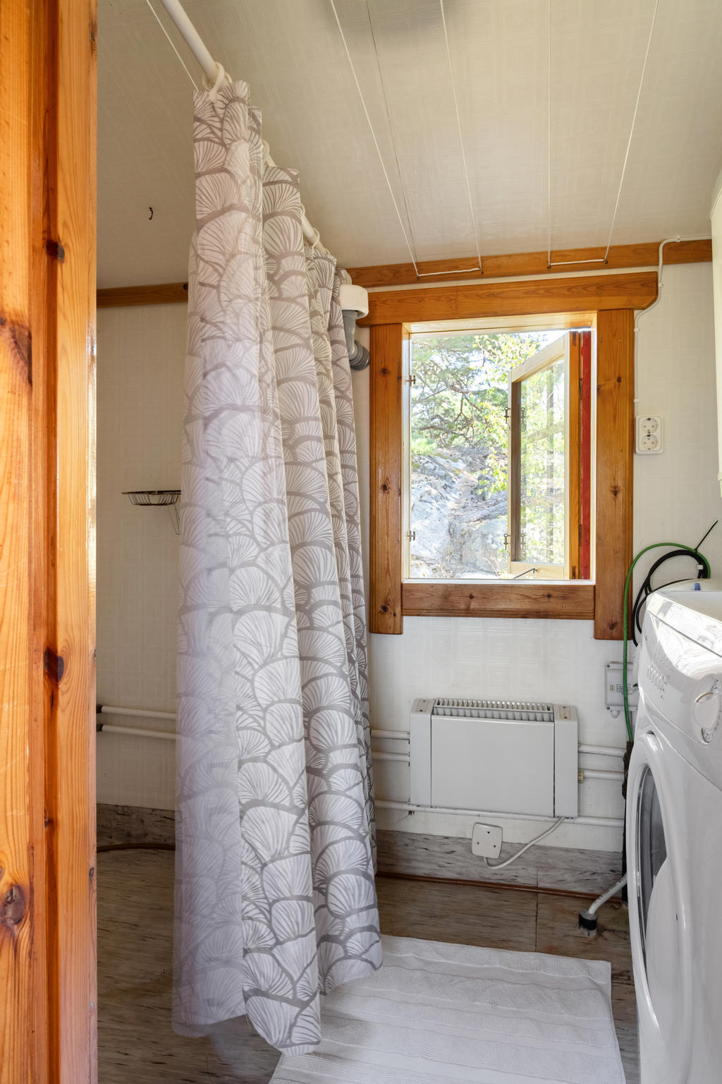Badrummet är praktiskt utformat med dusch och tvättmaskin. En välplanerad yta som förenar funktion och bekvämlighet.