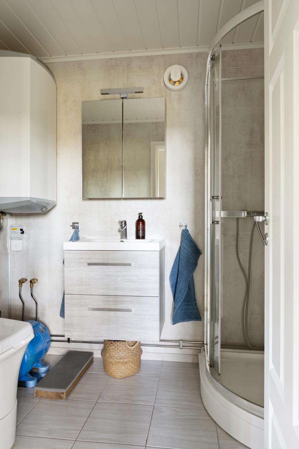 Fräscht badrum utrustat med toalett, duschkabin, handfat, kommod och spegel.