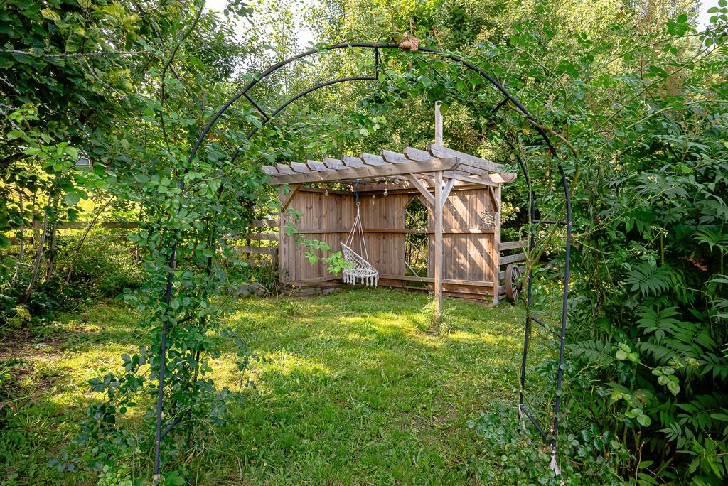 Bakom rosenbågen finns en liten pergola för skugga
