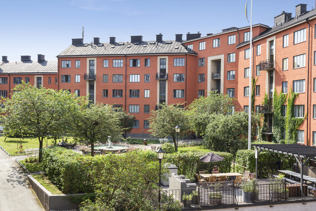 Grönskande innergård med flertalet uteplatser och grillar