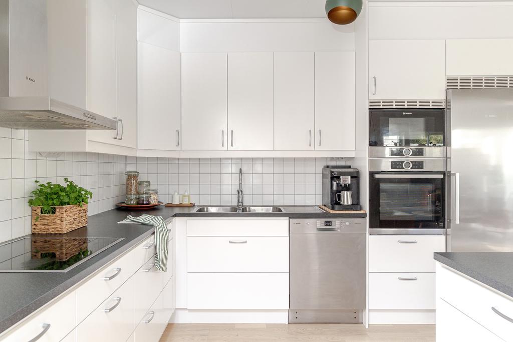 Den moderna inredningen i ljusa toner möter en mörk laminatbänkskiva för en snygg kontrast.