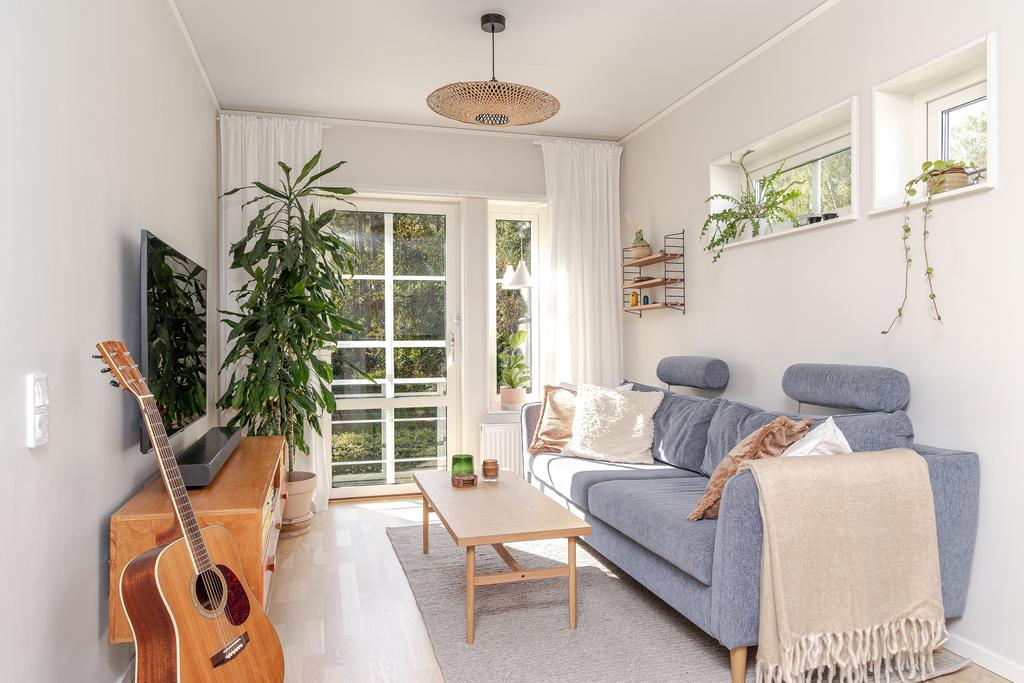  Här bjuds på utsikt mot naturen bakom huset och rummet ramas in av vitpigmenterat ekgolv och målade väggar.