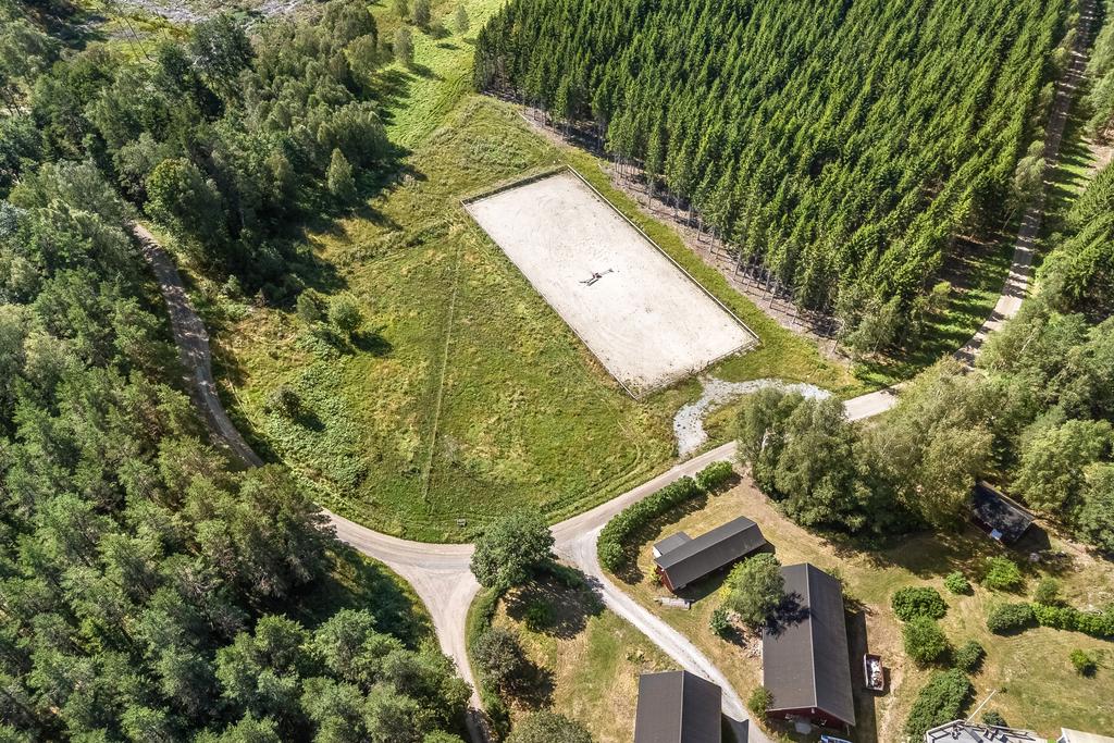 Vy över del av gårdstun och ridbanan (30x70m) + betesmark