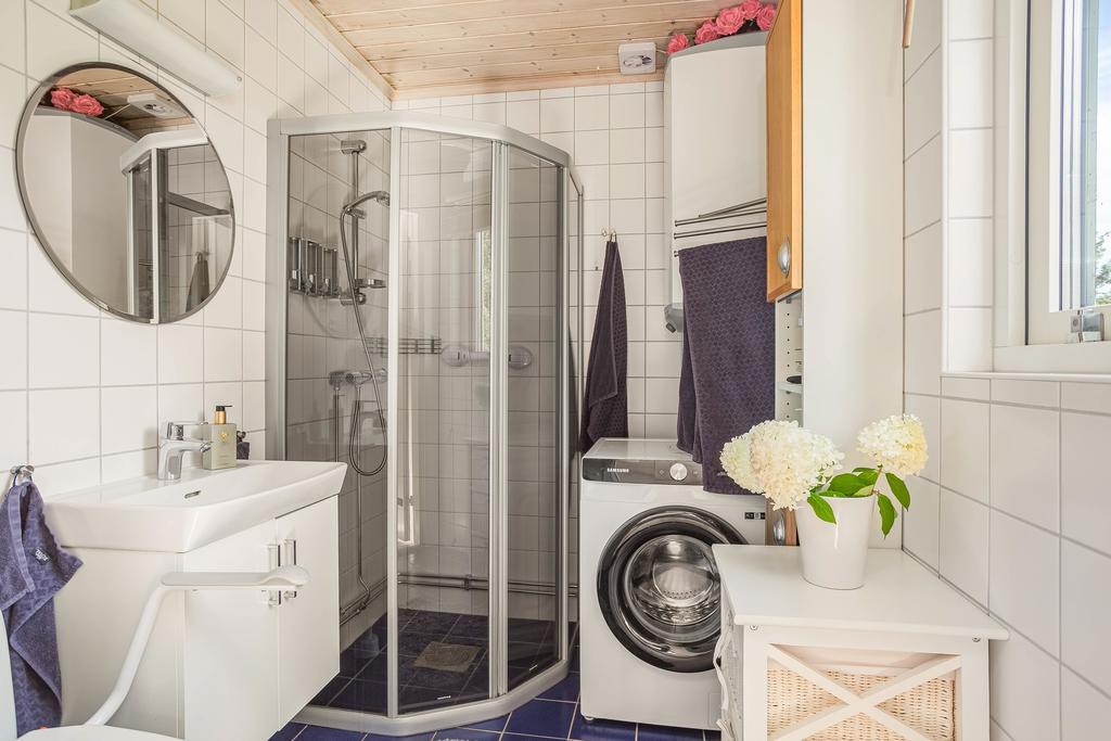 Badrum med dusch, tvättmaskin och förvaring.
