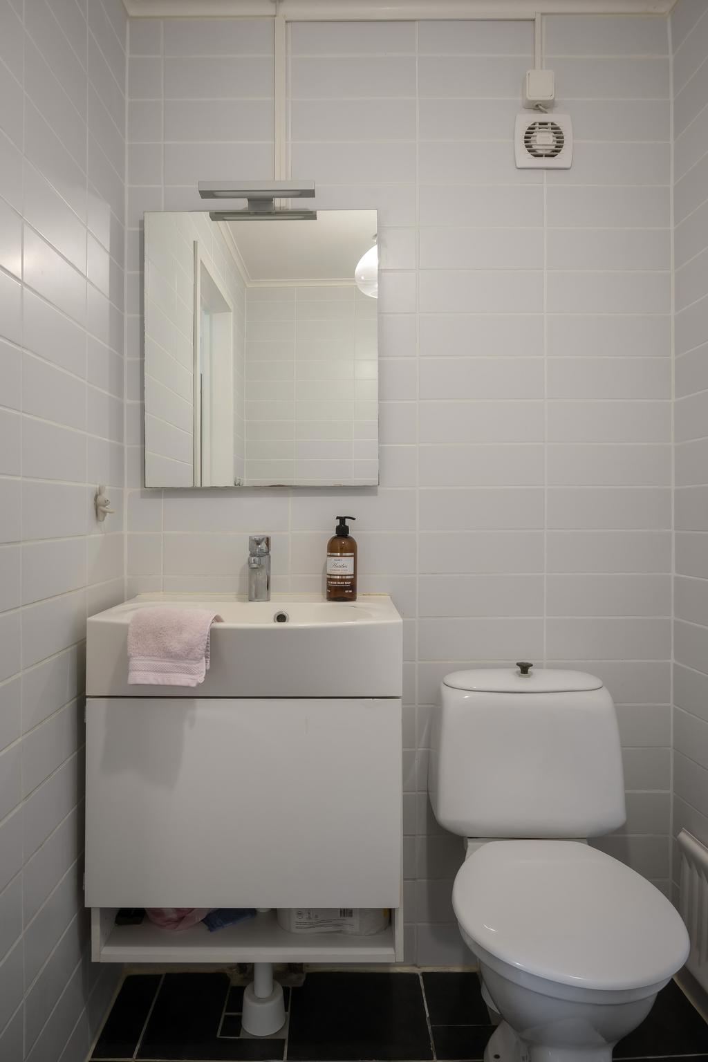 Helkaklat badrum med WC och tvättställ.