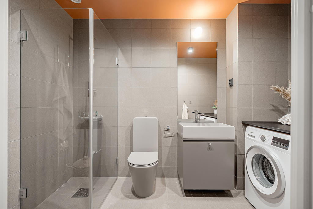 Smakfullt och modernt badrum utrustat med wc, handfat, dusch, tvättmaskin och torktumlare med avlastningsyta samt golvvärme.