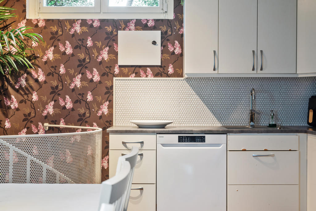 Vita luckor och lådförstycken, arbetsbänk i mörk laminat och stänkskydd i mosaikkakel.