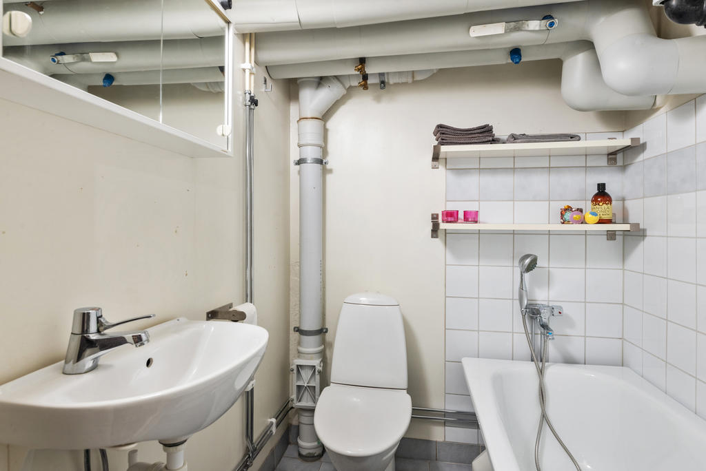 På nedervåningen finns ett tufft badrum med badkar, handfat med spegelskåp ovanpå