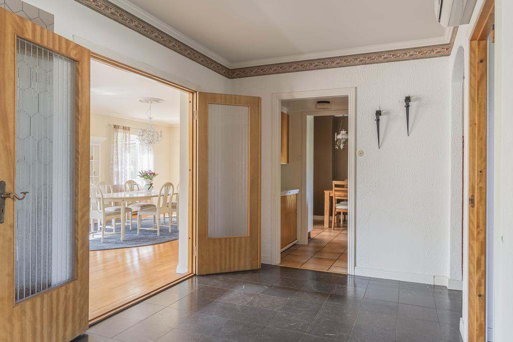 Entréhall sedd från annan vinkel med dubbla glasdörrar som öppnar upp mot husets sällskapsytor.