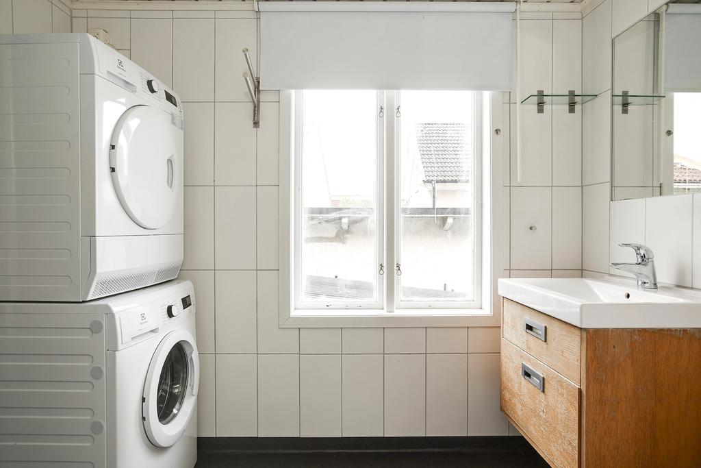Kombinerat badrum och tvättstuga med tvättmaskin, torktumlare, kommod och dusch