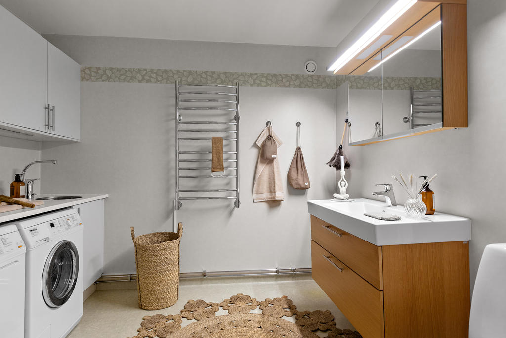 Rymlig tvättstuga utrustad med wc och handfat med kommod  