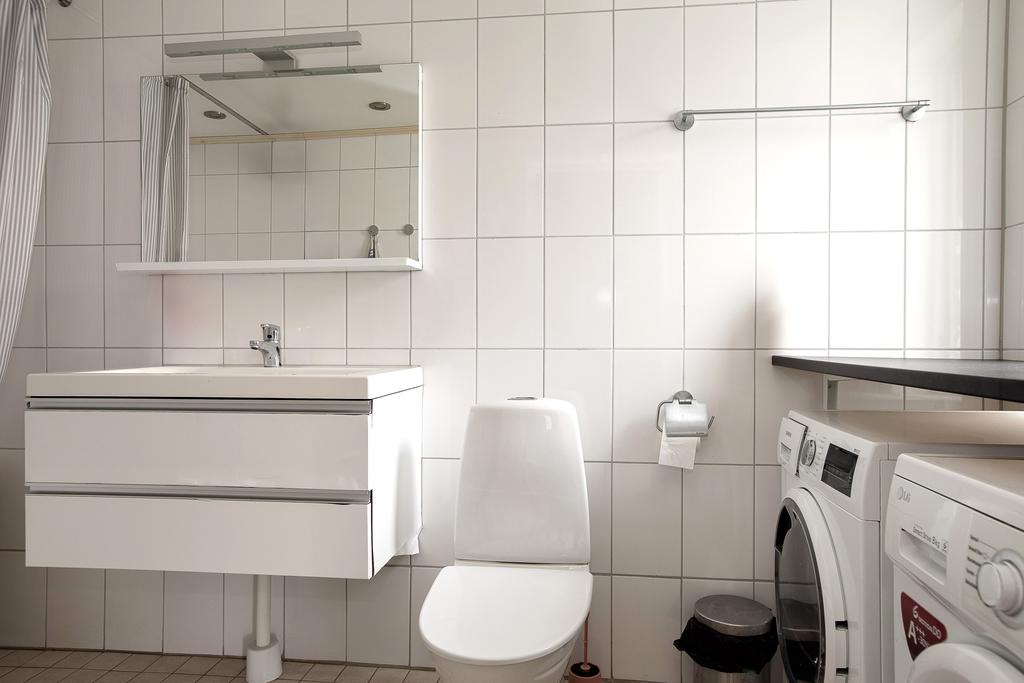 Badrum med tvättstuga, kommod, tvättmaskin och torktumlare samt badkar