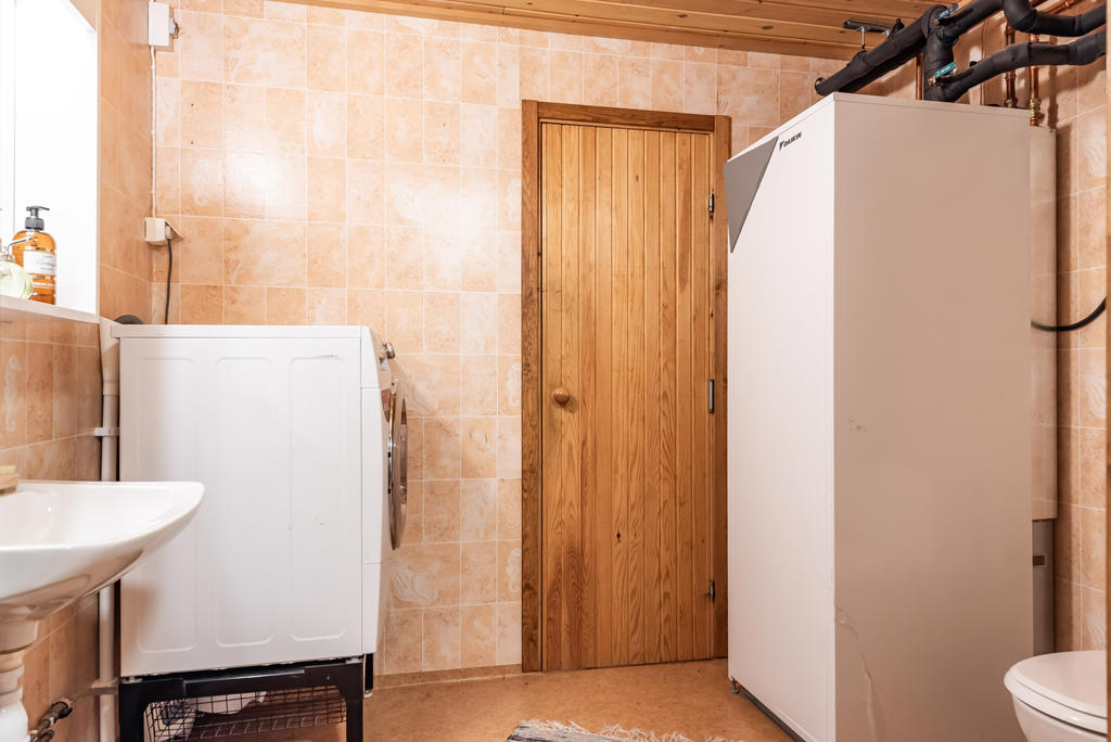 Tvättstugan har wc och tvättställ. Här är även bergvärmepumpen. Bakom dörren är ett förråd. 