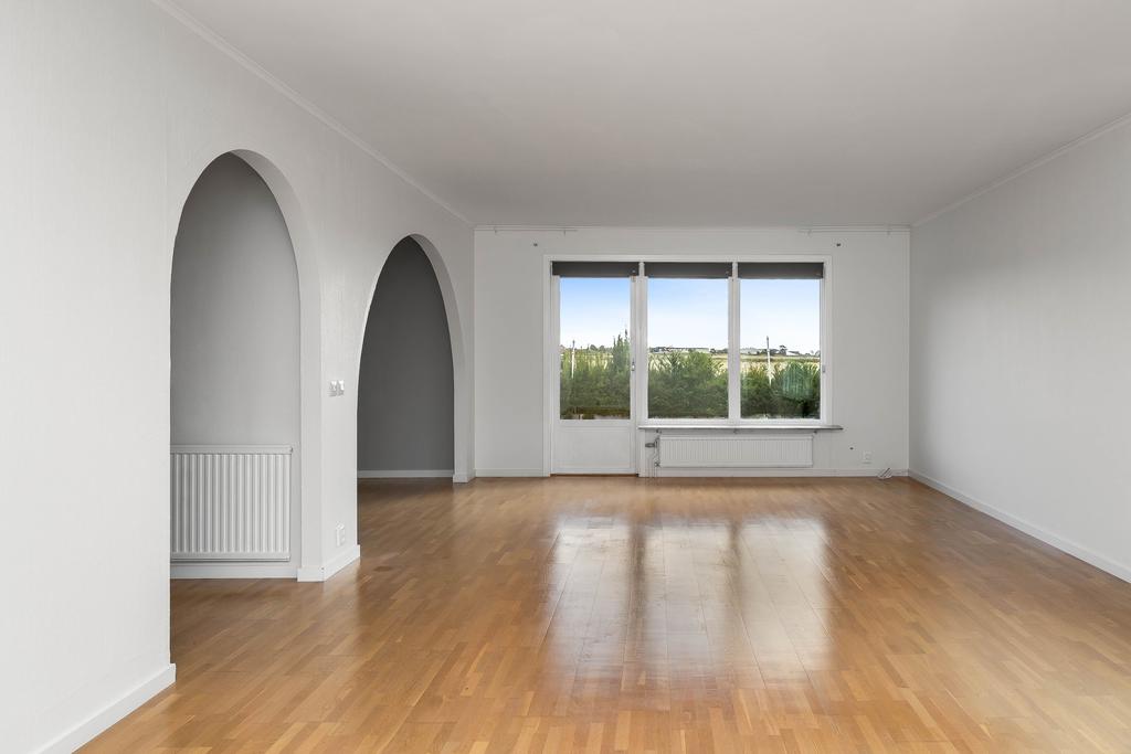 Vardagsrummet är rymligt med plats för olika möbleringar och fönsterparti mot altanen på baksidan av huset.
