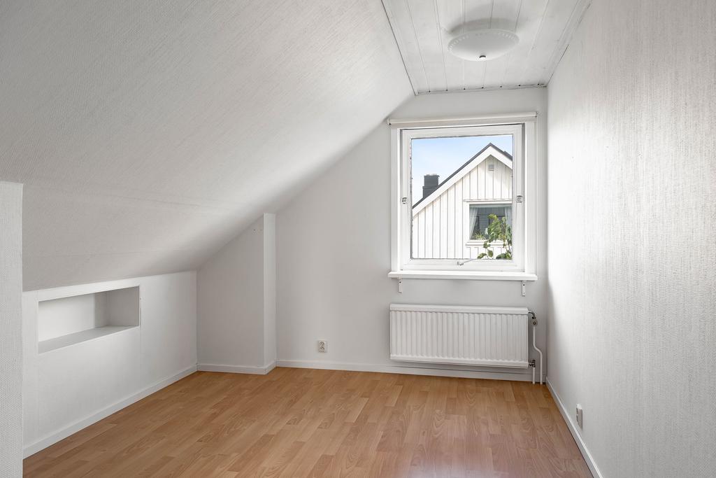 Detta sovrum har ljusa väggar och ljus laminatgolv. 