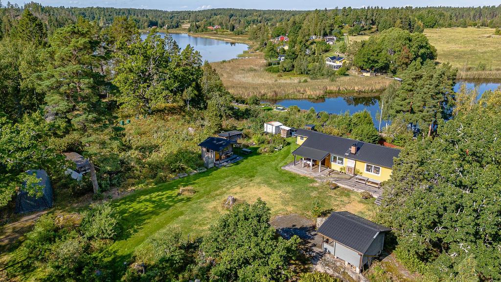 Gräsmatta på husets framsida och uppfart till huset längst ner till vänster i bild