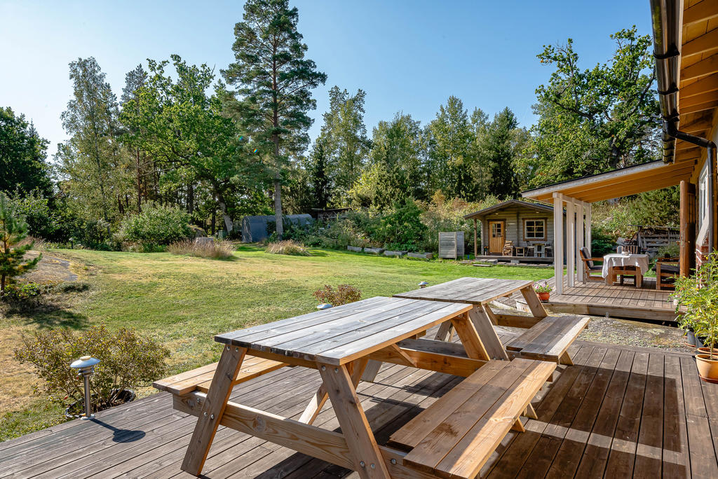Plana gräsytor framför huset och bastuhuset längst bort i bild