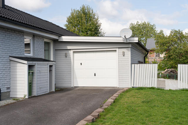 Vidbyggt garage med plats för bil och redskap.