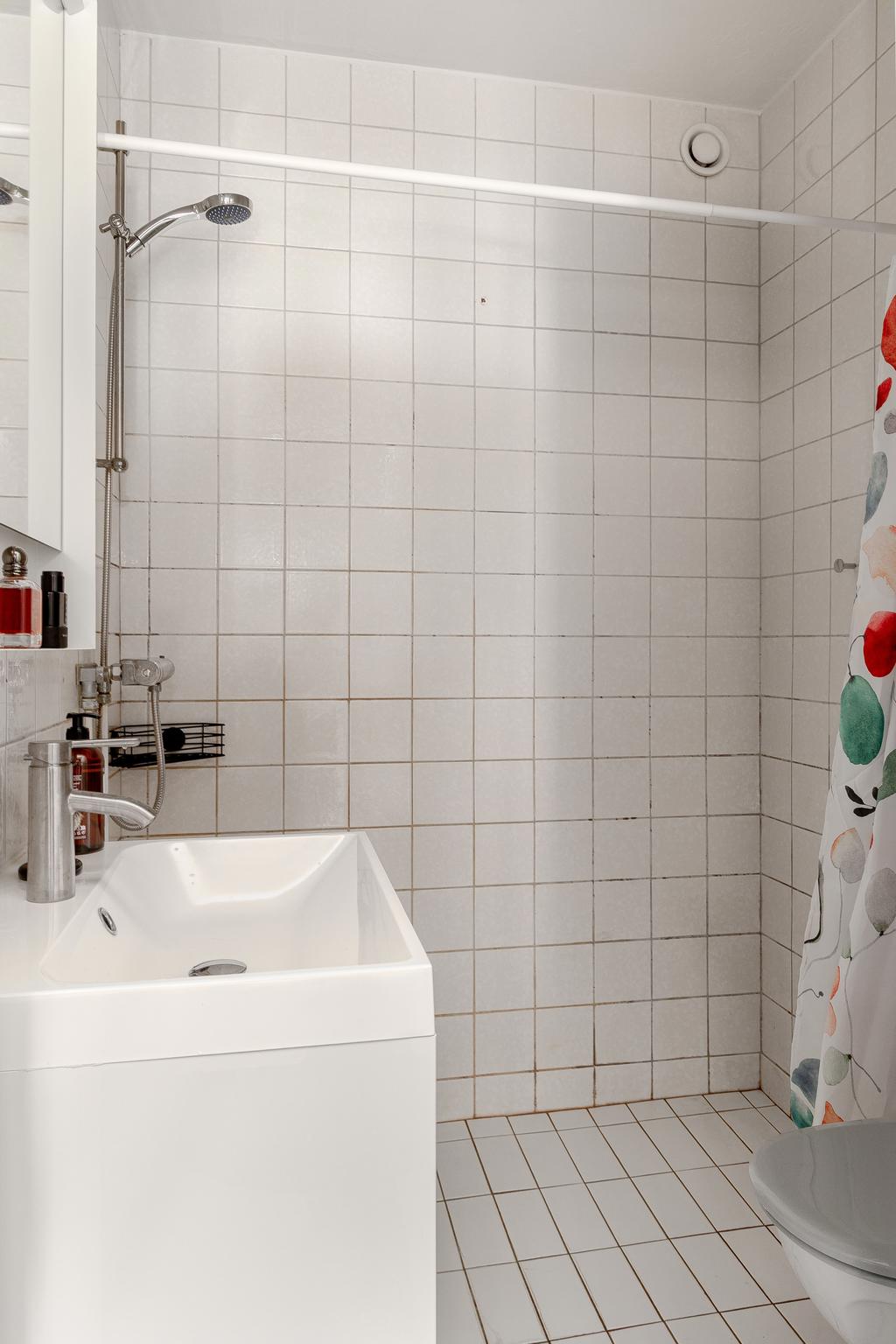 Stilrent badrum med helkaklade väggar, dusch och moderna detaljer.