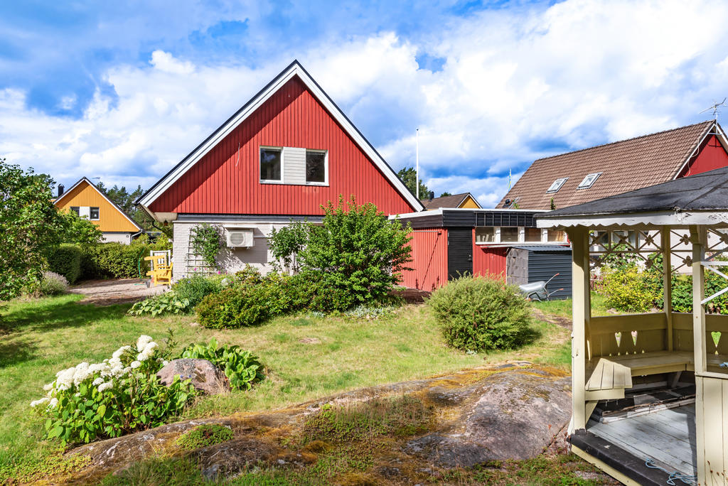 Baksidan på tomten med lusthus och ingång till förråd och garage