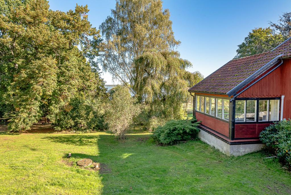 Gräsmatta och trädgård mellan f.d stall och bostadshus