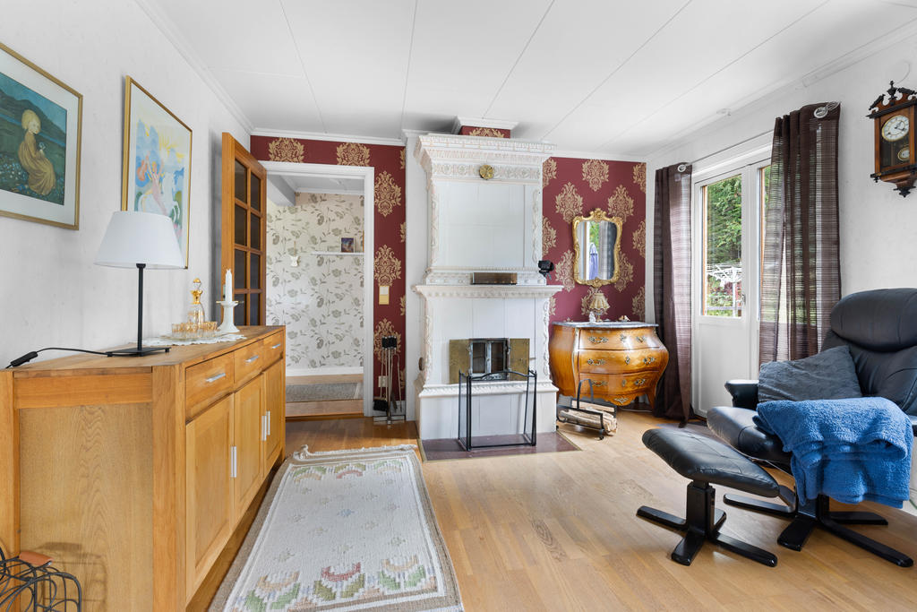 Vardagsrum i vinkel med fungerande kakelugn och plats både för matbord och soffgrupp