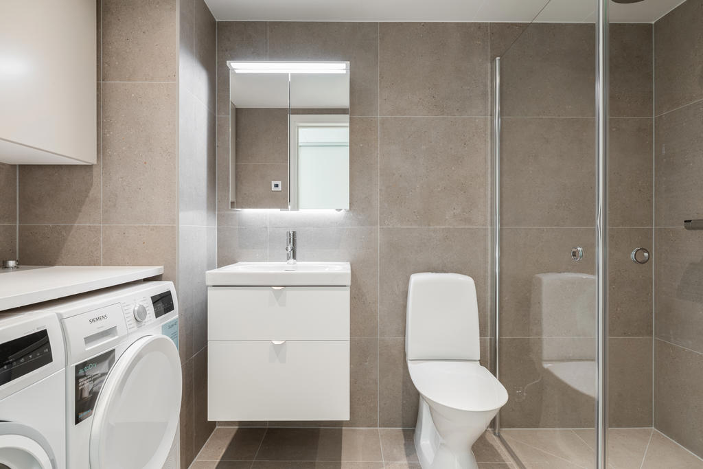 Helkaklat badrum med tvättmaskin och torktumlare