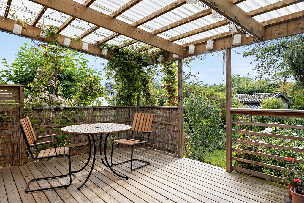 Trevlig altan under tak i anslutning till den lummiga trädgården