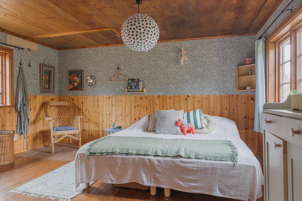 Rofyllt sovrum med smakfulla detaljval, vacker träpanel och harmoniska färger.