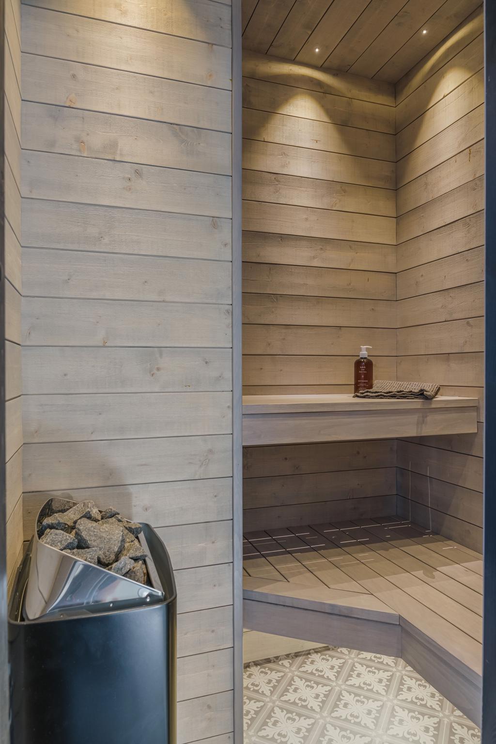 Ljus och modern bastu med träpanel, sittbänkar i två nivåer och bastuaggregat.