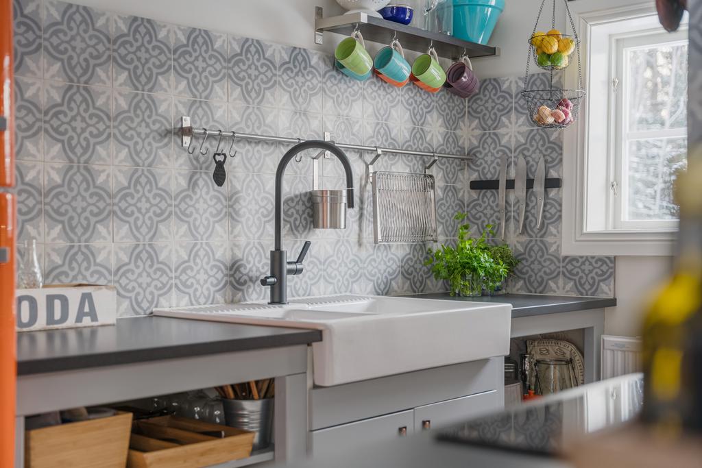 Detaljbild av köket med diskho, arbetsyta och dekorativt kakel.