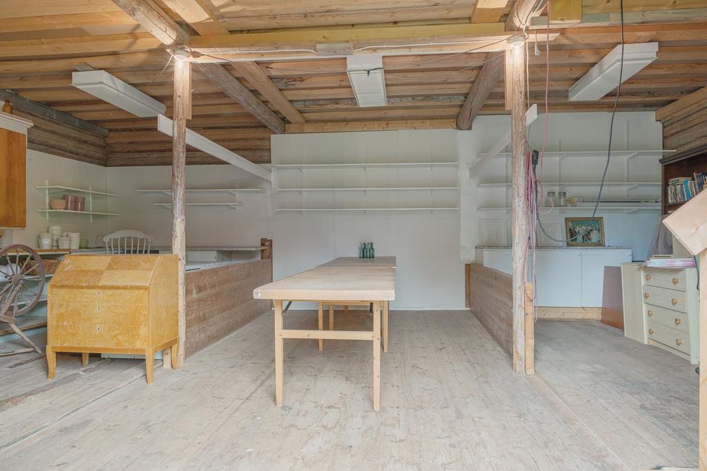 Rymligt utrymme i ladan med trägolv och gott om plats för förvaring, hobbyverksamhet eller framtida projekt.