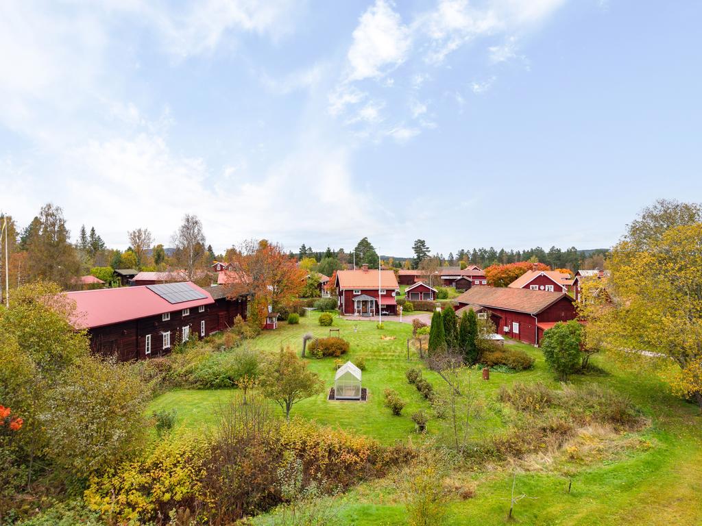 Välskött gård i vackert byläge med flera byggnader och grönskande omgivningar.