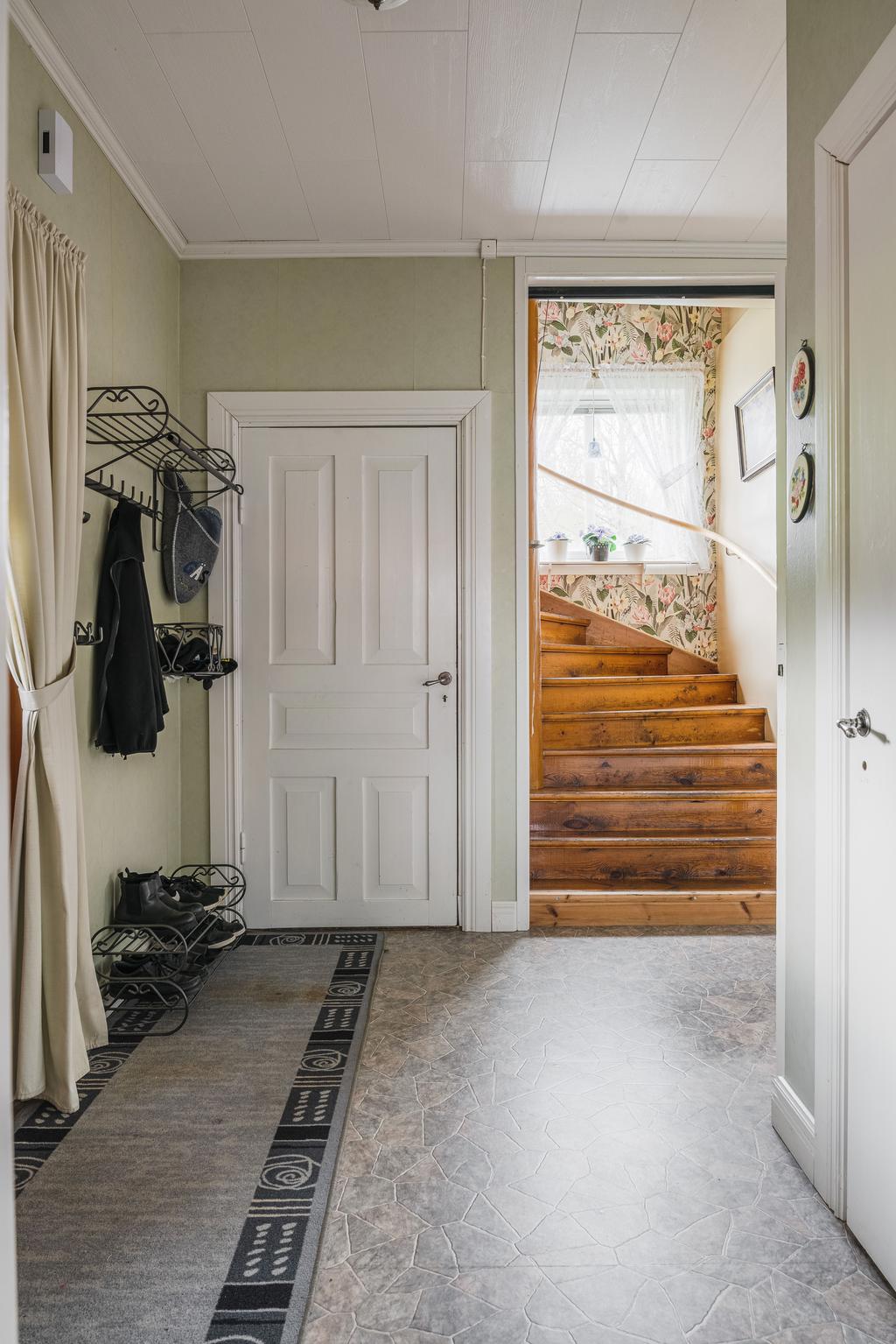 Hall med plats för ytterkläder och trappa till övre plan.