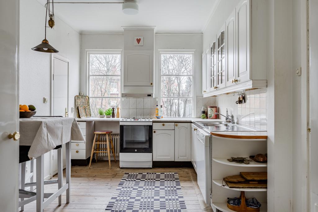 Kök med fina fönsterpartier, trägolv och skafferi