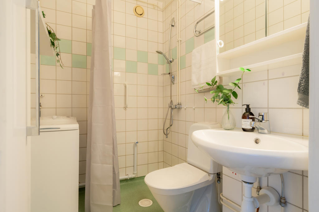 Kaklat badrum med dusch och tvättmaskin