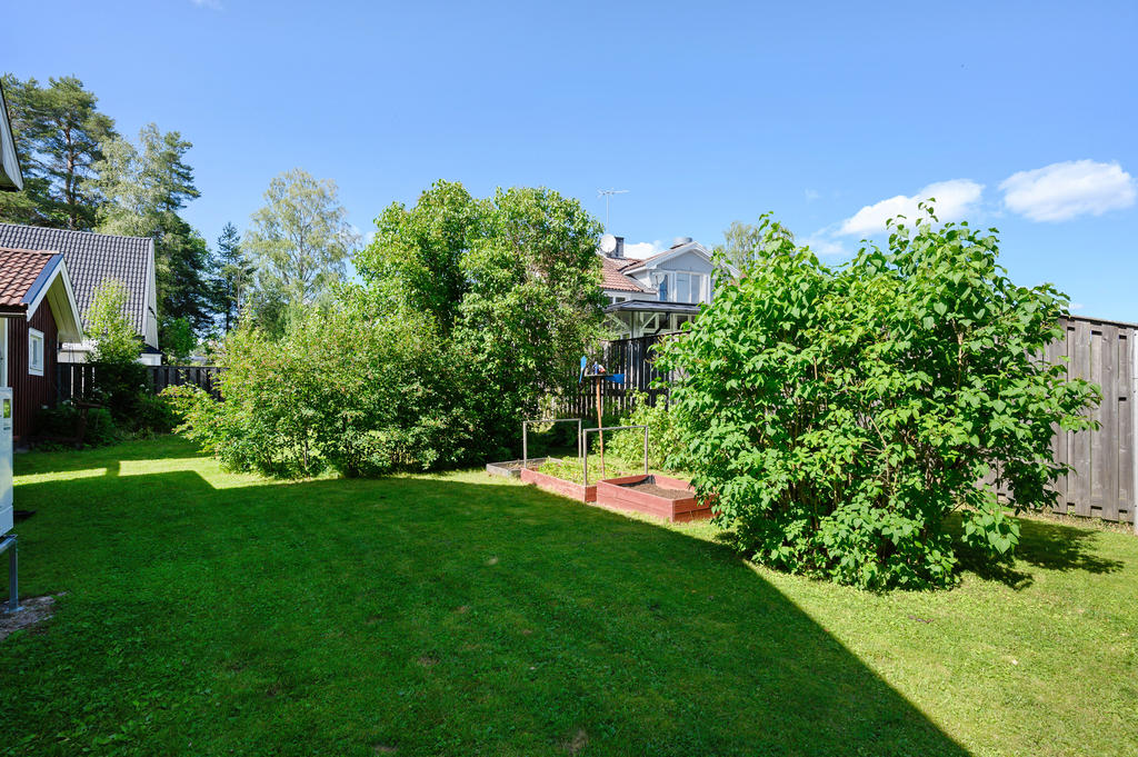 Trädgård med odlingslådor och plats för lek