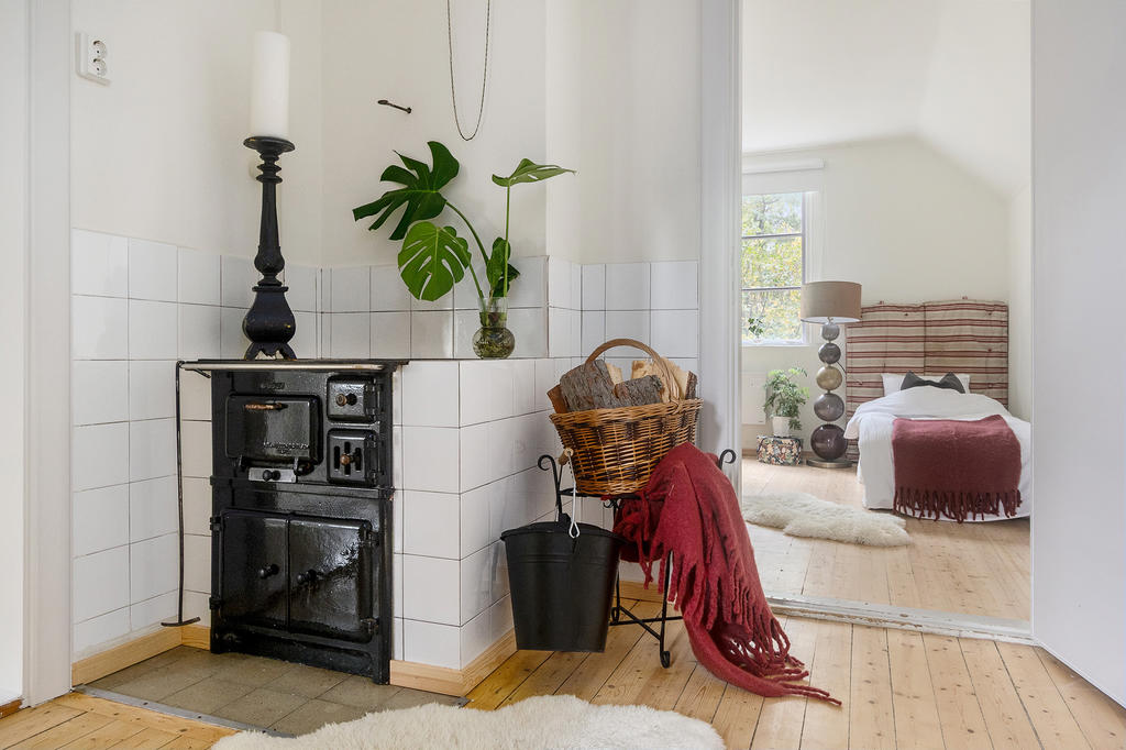 Övre hall med en charmig gammal vedspis och ett mysigt sovrum under snedtaket.