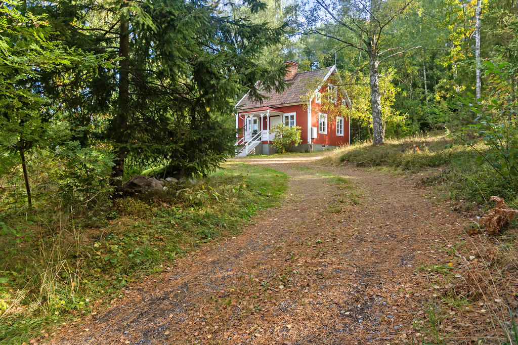 Grusad uppfart genom grönskan fram till sekelskifteshuset. Avskilt och privat, men ändå nära grannar och vägen ut.