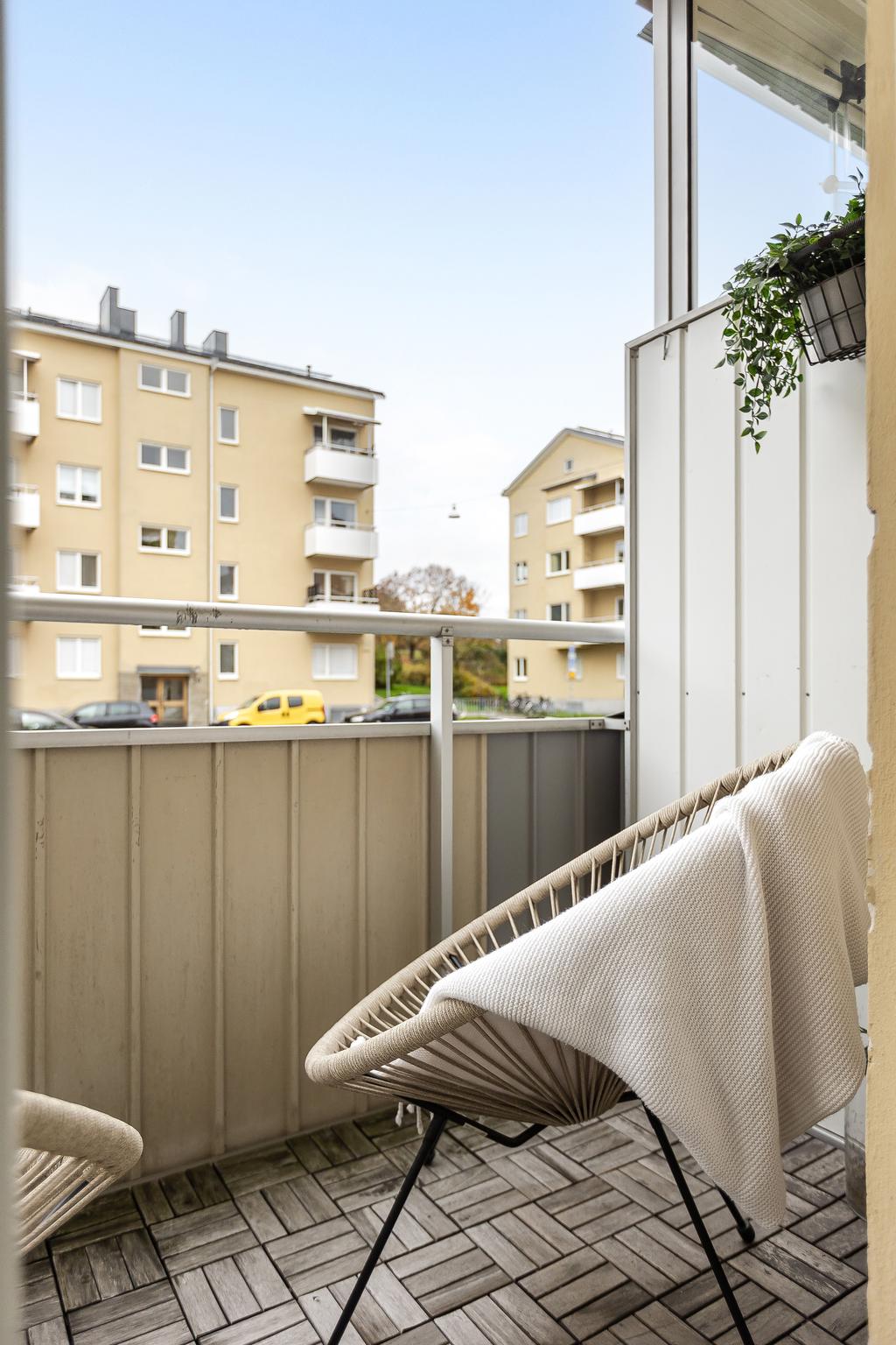 Balkong med trätrall och plats för ett par fåtöljer