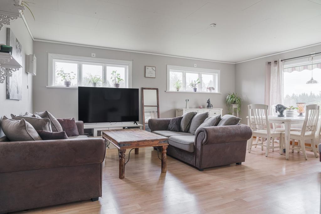 Rymligt och ljust vardagsrum med flera fönster som släpper in rikligt med dagsljus och skapar en trivsam atmosfär. 