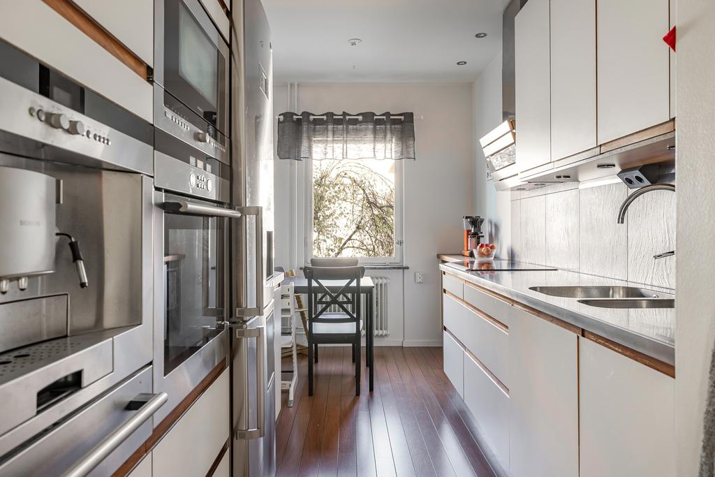 Kök med vita släta luckor och plats för matbord invid fönstret