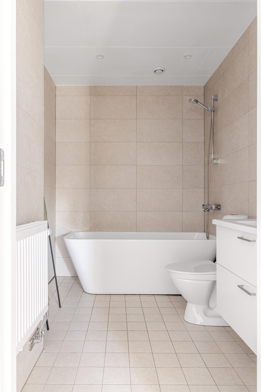 Badrum på övreplan, med badkar. Kakel och klinker i beige.