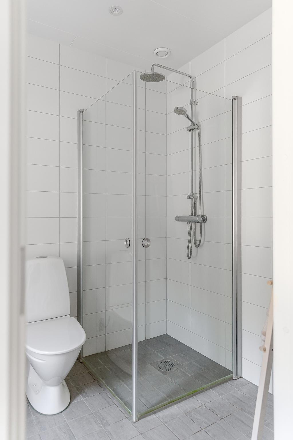 Kakel och klinkers i vitt och grått. Takdusch. 