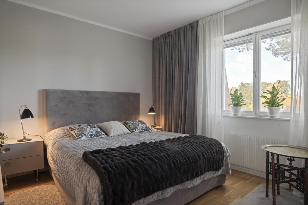 Sovrummet ligger på lägenhetens svalare sida. Persienner i fönstren. 