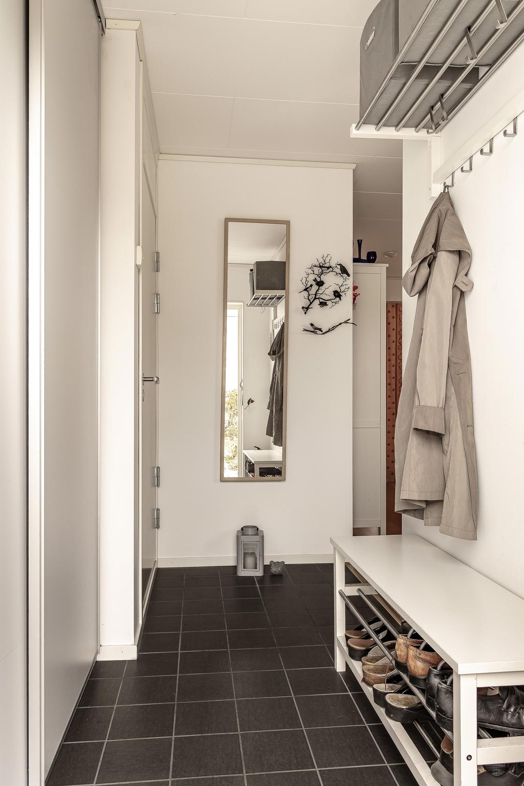 Hall med klinkergolv och plats för avhängning direkt innanför dörren.