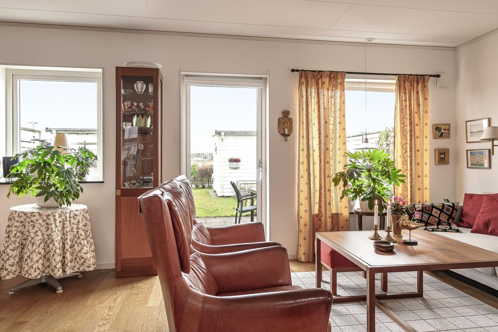 Vardagsrummet har stora fönsterpartier som släpper in rikligt med dagsljus och ger utsikt mot uteplatsen.