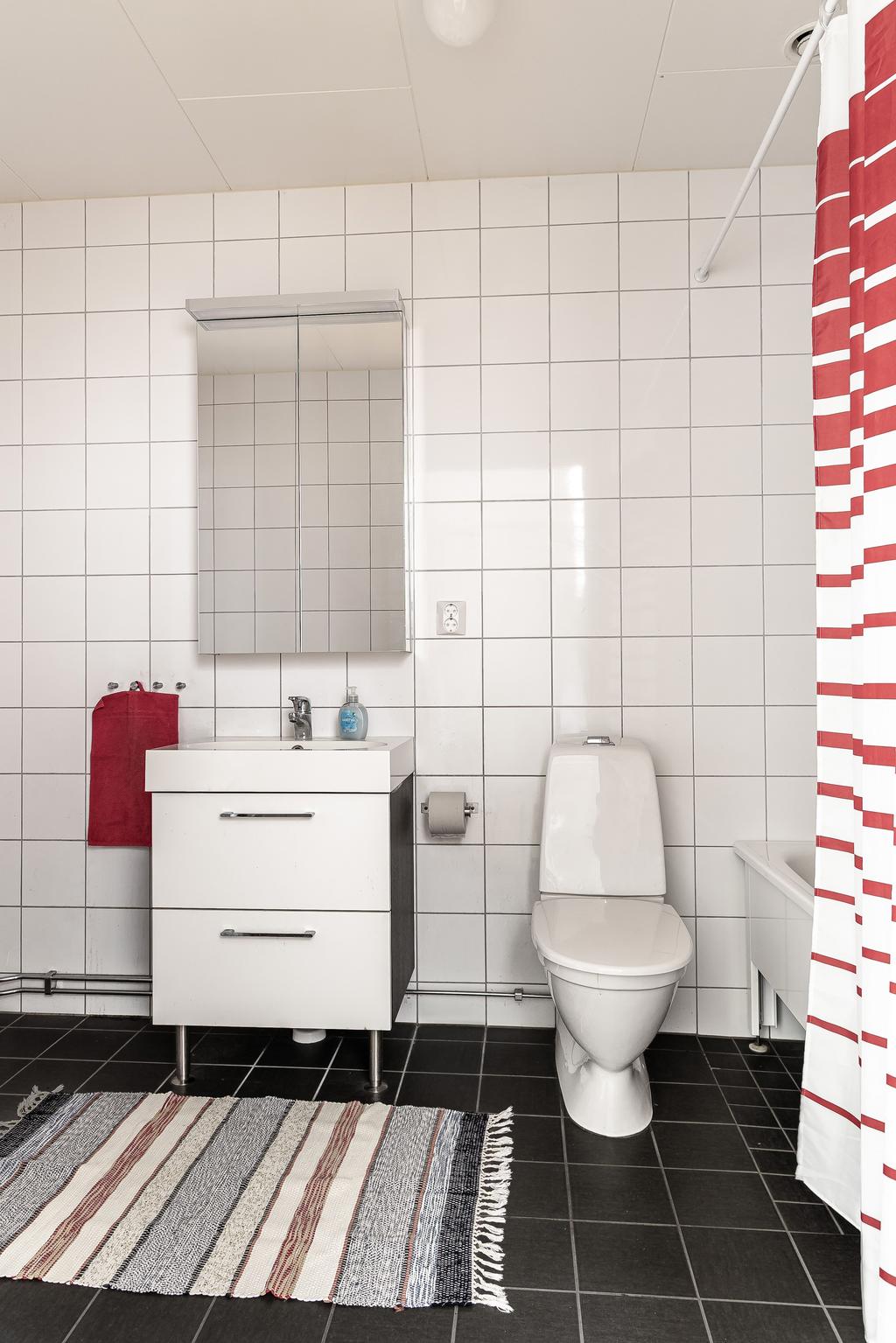 Helkaklat badrum utrustad med spegelskåp, kommod och badkar.