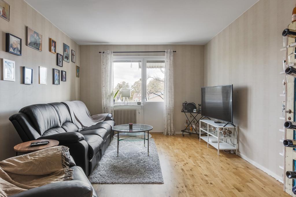 Vardagsrum med parkettgolv och utgång till balkong i västerläge