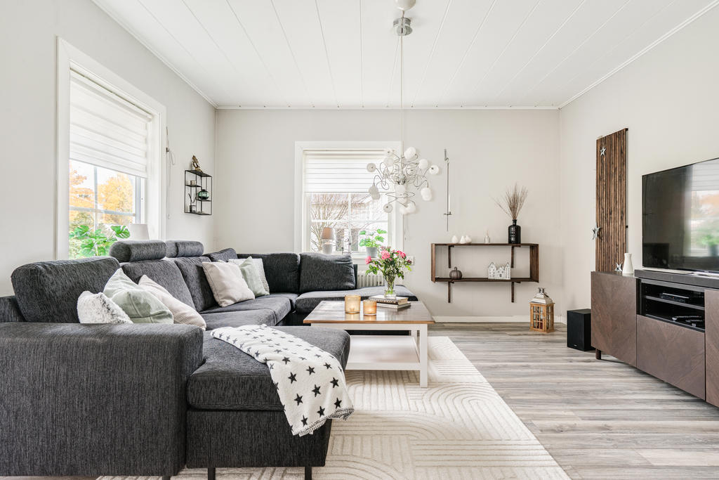 Hemtrevligt vardagsrum med varma färger och fina ytskikt samt utgång till altan delvis  under tak. 